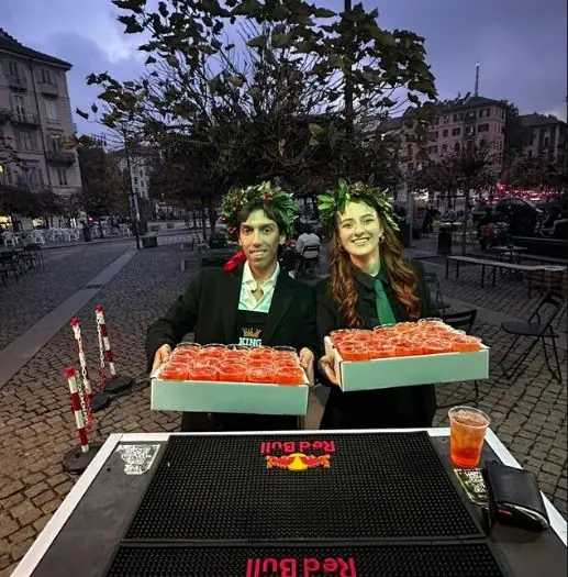 Due neolaureati con i vassoi di spritz di notte