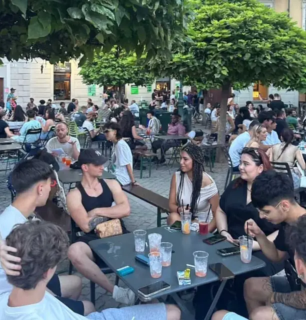 Tavolini pieni in piazza, ogni sedia occupata