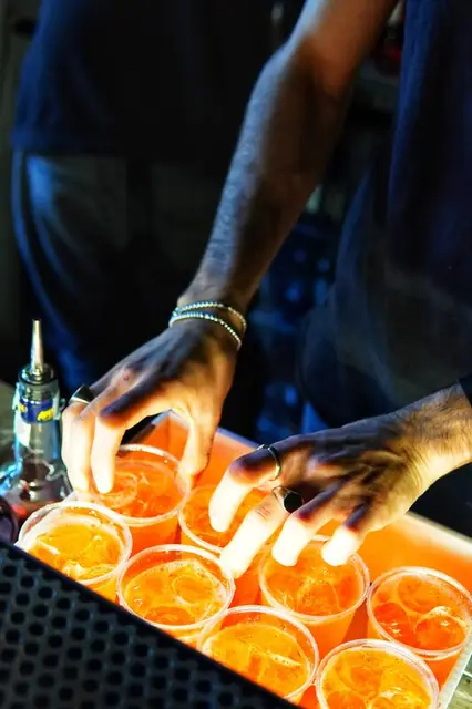 Mani che sistemano bicchieri di spritz illuminati